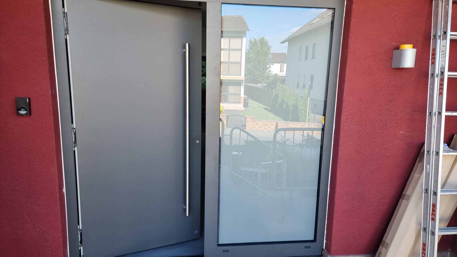 Moderne graue Aluminium-Haustür mit Glas-Seitenteil, rote Fassade
